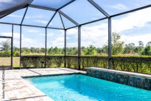 Modern contemporary home villa with screened in glass canopy lanai private pool with view of tropical lake in Florida with blue water in clean house